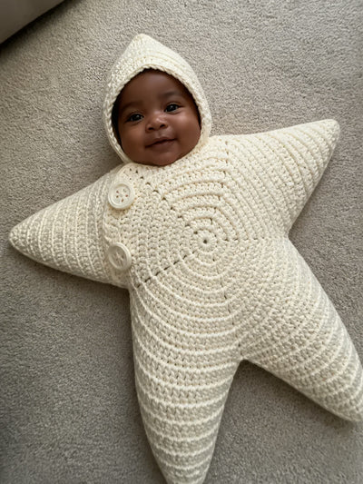 Hand-crocheted starfish suit in Cloud White, on a baby