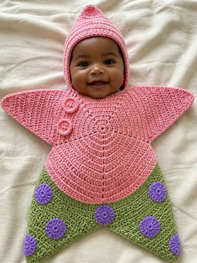 Hand-crocheted starfish suit in Pinky Green, on a baby